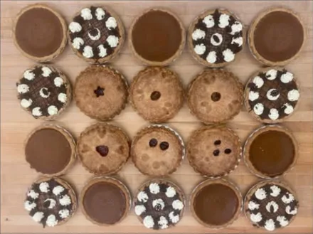 Pies on a wooden board: pumpkin, chocolate with cream, and fruit pies with a lattice of cut-outs